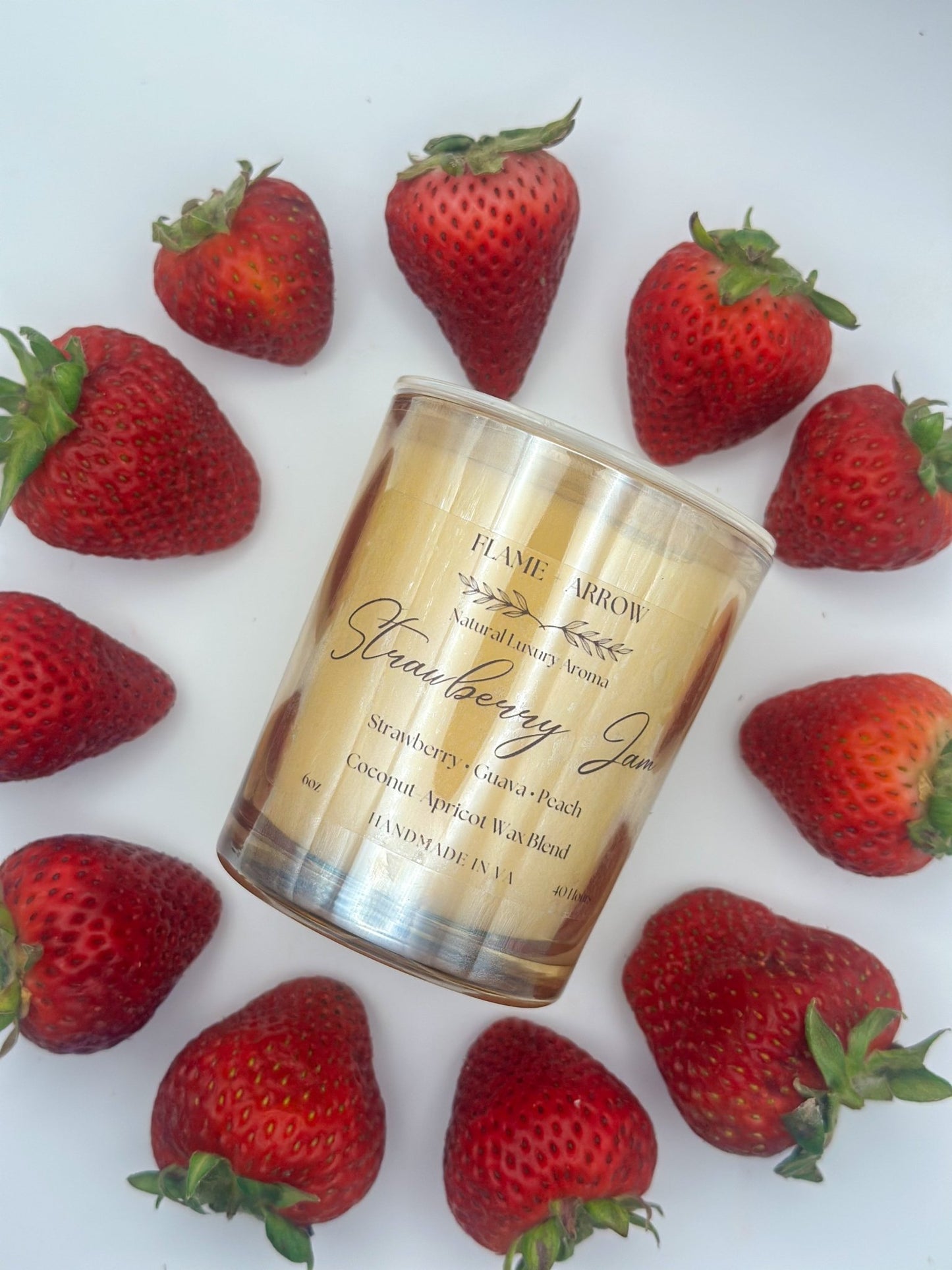 Candle labeled 'Strawberry Jam' surrounded by strawberries on a white background