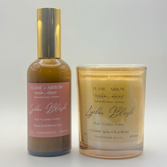 A bottle of Lychee Room Spray next to a coconut apricot wax natural candle also scented in Lychee Blush.